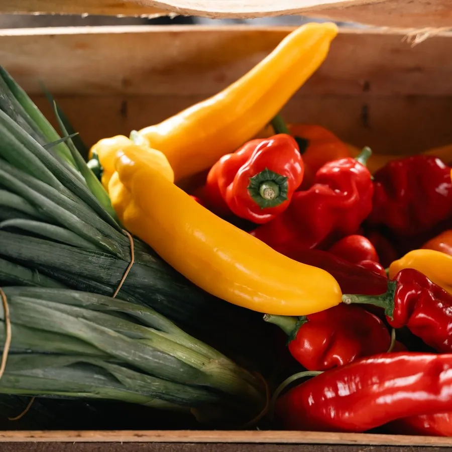 Peti kayu berisi daun bawang, paprika, dan cabai